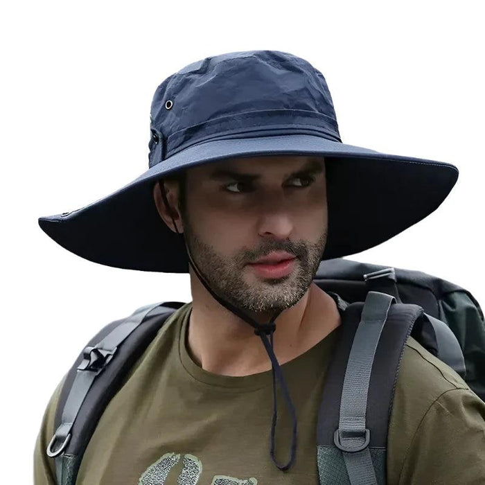 Man wearing a wide-brimmed navy blue sun hat while hiking, with a backpack on his shoulders. The hat provides sun protection, perfect for outdoor activities such as hiking and camping.