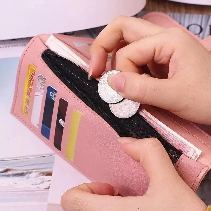 A close-up of hands holding a pink wallet, inserting coins into its zippered compartment. The wallet has multiple card slots visible.