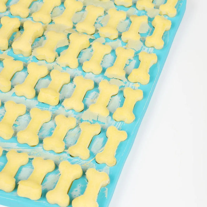 Blue dog bone silicone mold filled with yellow dough.