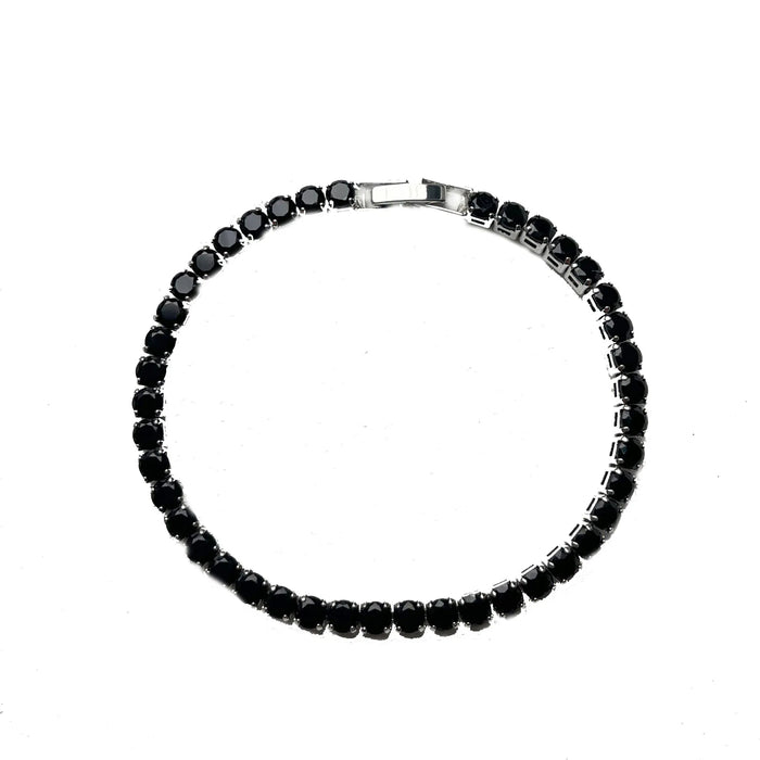 Silver tennis bracelet with black stones on a white background.