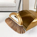 A gold broom with brown bristles, attached to a gold dustpan with a comb edge, designed for effective sweeping and cleaning.