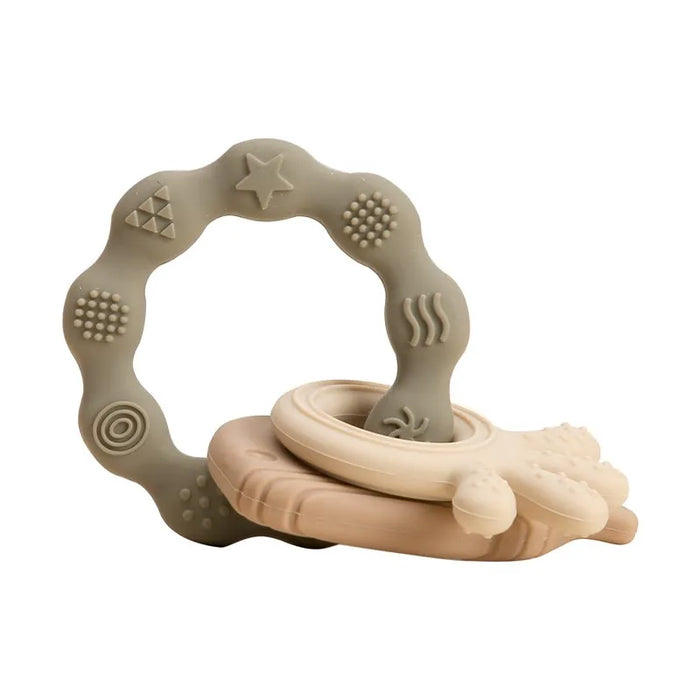 A gray silicone teether ring with various beige and cream textured patterns.