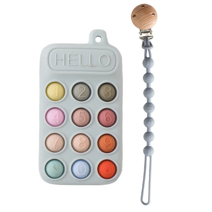 A blue silicone teether resembling a phone keypad with colorful buttons, next to a pacifier clip with a wooden clasp and pink silicone beads.