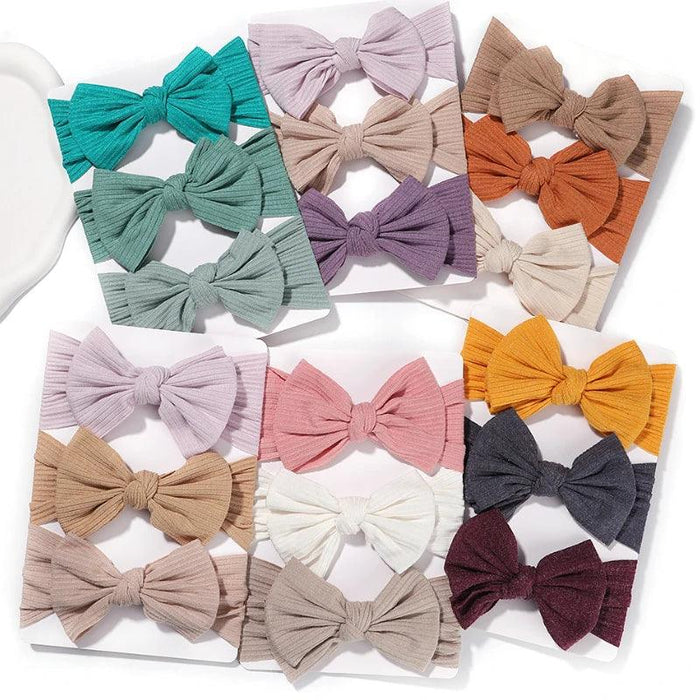 a collection of colorful ribbed fabric bow headbands arranged in sets of two on display cards.