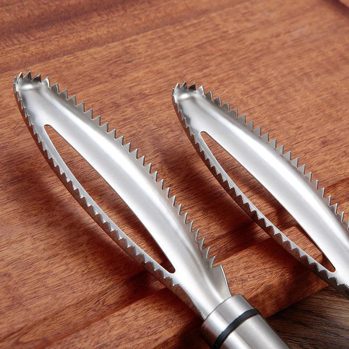 a close-up of two serrated, stainless steel fish scalers placed on a wooden surface.