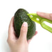 A person using a green avocado slicer to cut an avocado in half.