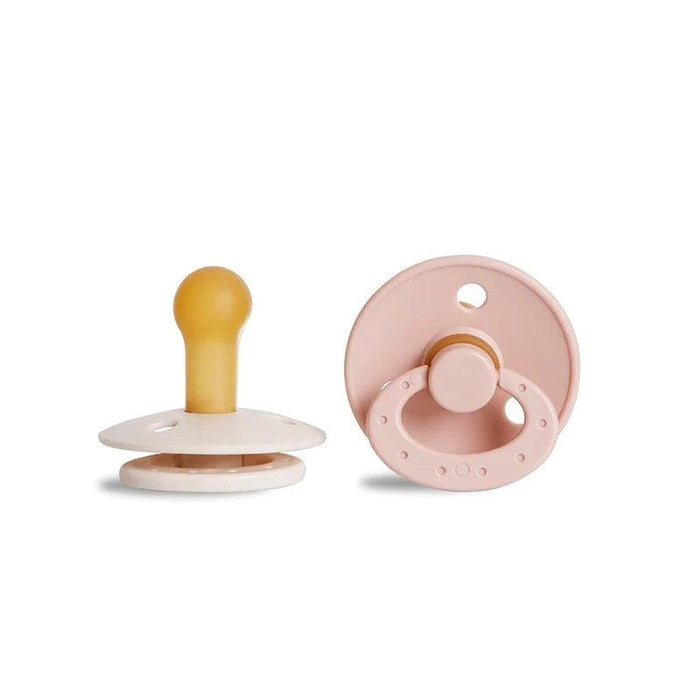 A beige pacifier with a yellow nipple and a pink, round pacifier with a ring handle.