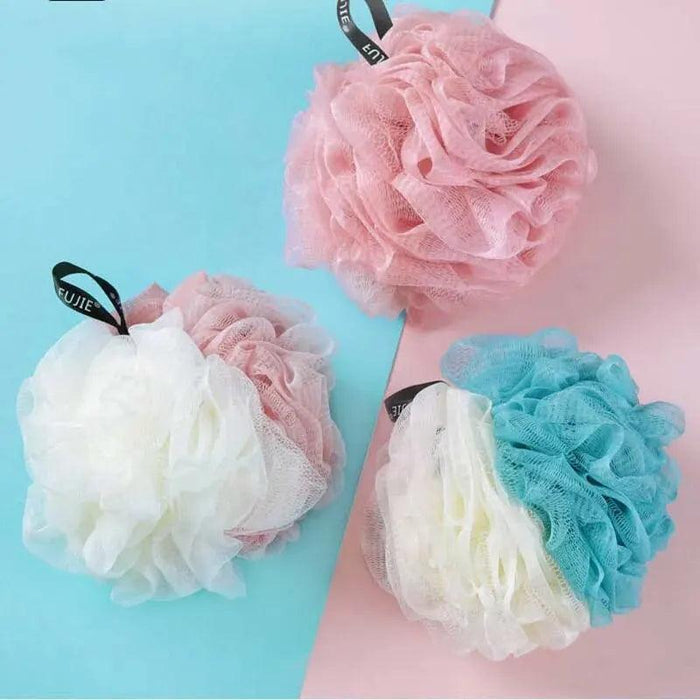 Three bath loofahs in different color combinations (pink and white, blue and white, and solid pink) displayed on a two-tone blue and pink background.