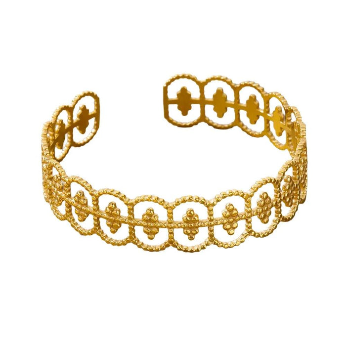 Gold cuff bracelet with a delicate lace-like pattern, displayed on a white background.