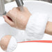 A person's hand under running water, wearing a white fluffy wrist towel to prevent water from running down the arm.