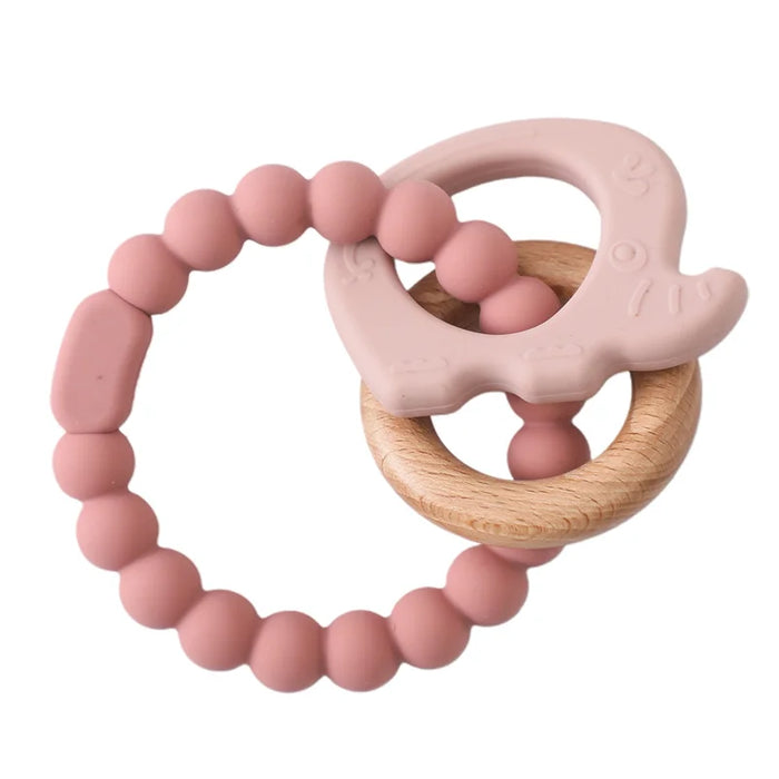 A teething ring set with pink silicone beads, a wooden ring, and a light pink silicone elephant-shaped charm.