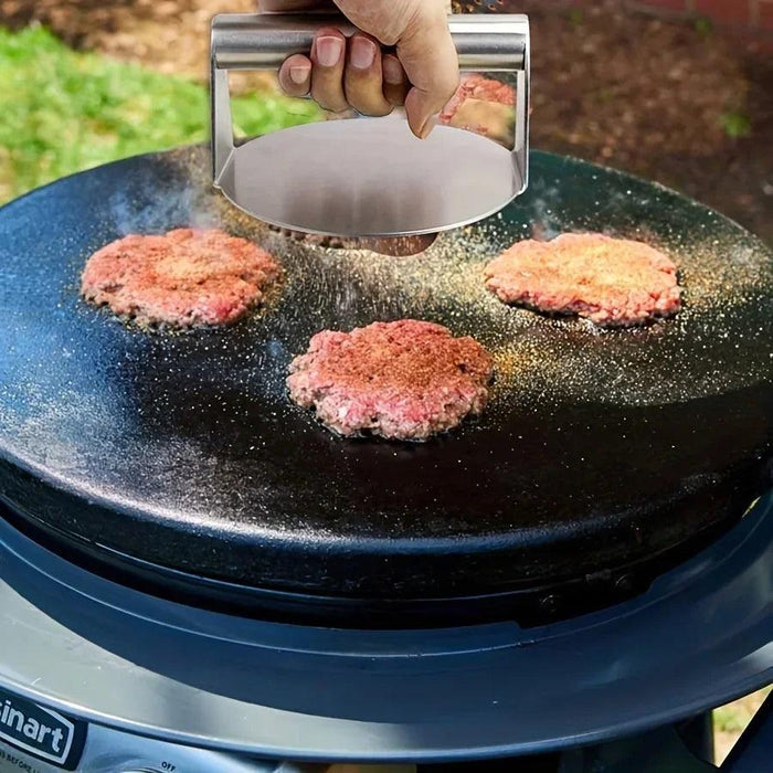 The grill press flattening burgers on an outdoor grill, demonstrating its functionality in achieving evenly cooked patties.