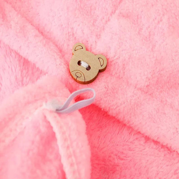 A close-up shot of a pink towel featuring a wooden button in the shape of a bear's face, highlighting its soft and fluffy texture.