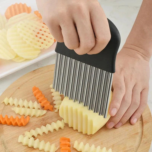 A person using a crinkle cutter to slice a potato on a wooden cutting board, demonstrating the tool's functionality in creating crinkle-cut vegetable slices.