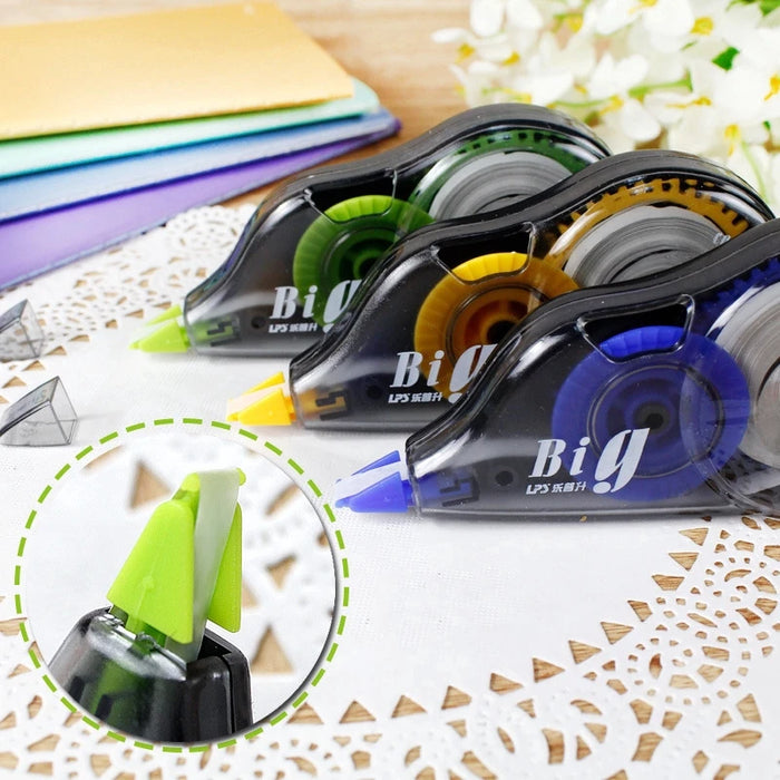 Assorted correction tape dispensers with visible tape rolls in a variety of colors displayed on a lace tablecloth.