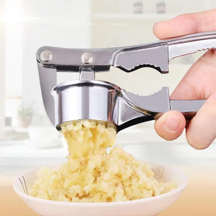 A metal garlic press squeezing minced garlic into a bowl, with the hand operating the press in focus.