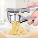 A metal garlic press squeezing minced garlic into a bowl, with the hand operating the press in focus.