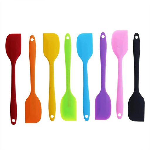 A collection of eight silicone spatulas in various colors: red, orange, yellow, green, blue, purple, pink, and black. Each spatula has a hole at the end of the handle for easy hanging and storage.