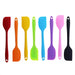 A collection of eight silicone spatulas in various colors: red, orange, yellow, green, blue, purple, pink, and black. Each spatula has a hole at the end of the handle for easy hanging and storage.