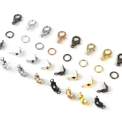 An assortment of jewelry findings, including lobster clasps, crimp beads, and jump rings, neatly arranged by color on a white background, demonstrating their variety and organization.