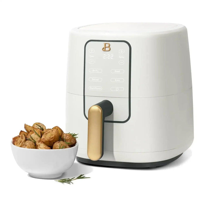 A sleek white air fryer with a gold handle and digital display, featuring various cooking options, is shown next to a bowl of roasted potatoes garnished with rosemary.