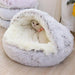 A fluffy pet bed with a white cat inside, looking towards the camera.