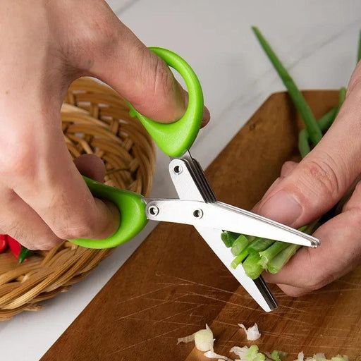 Open green-handled herb scissors cutting fresh green onions.