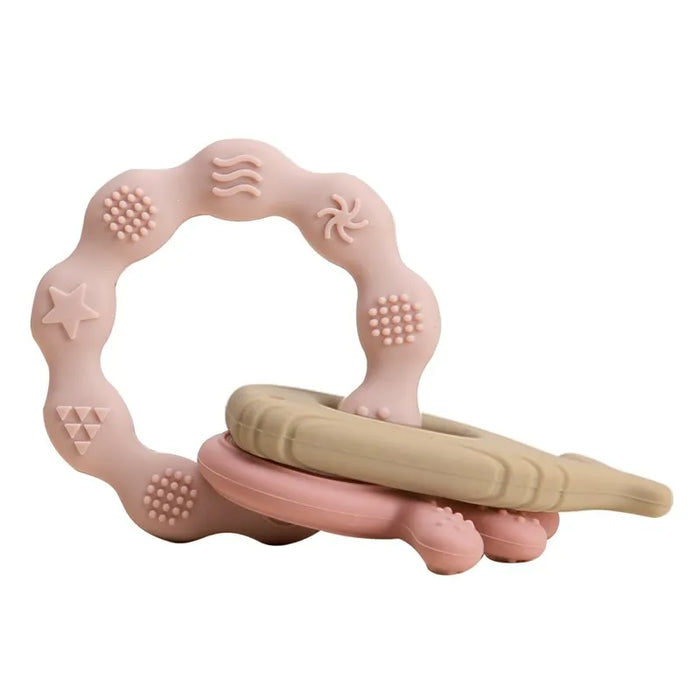 A light pink silicone teether ring with various beige and pink textured patterns.