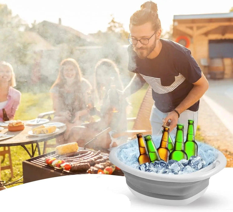 A man at a barbecue, using the collapsible wash basin filled with ice to chill beverages.