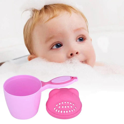 A close-up of a pink baby rinse cup next to a child in a bubble bath, showcasing the cup's detachable strainer lid.