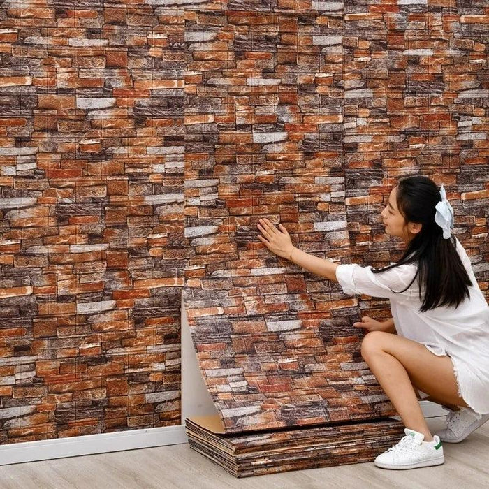 A person applying a wall panel with a stacked stone design in shades of brown and gray.