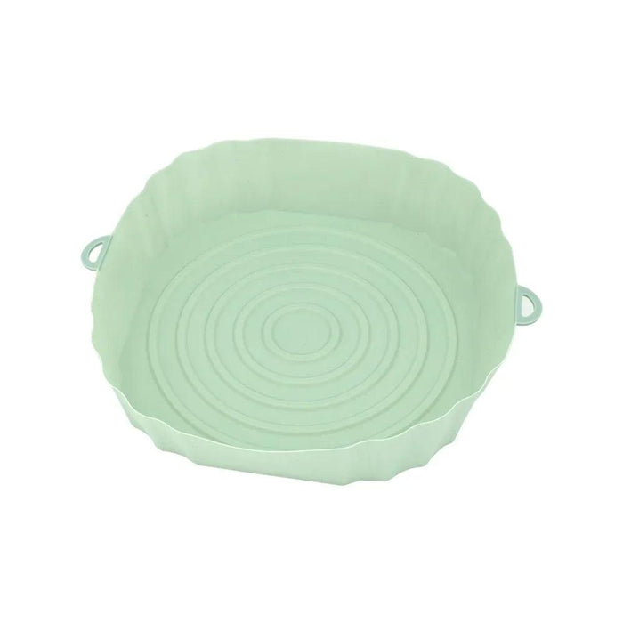 An empty mint green silicone air fryer liner with a spiral design at the bottom, placed on a white background.