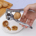 A metal nutcracker cracking a walnut, with shelled walnut pieces on a white plate.