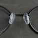 a close-up of a pair of eyeglasses with transparent silicone nose pads attached to the black frame, highlighting their soft and comfortable design.