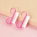 two pink nail brushes with white bristles placed on a pink and beige surface.