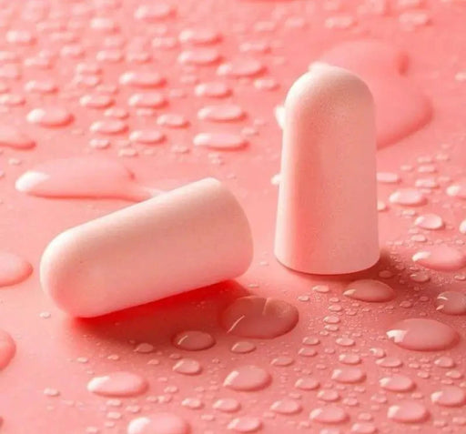 Close-up of two pink earplugs with water droplets on them. Displayed on pink background.