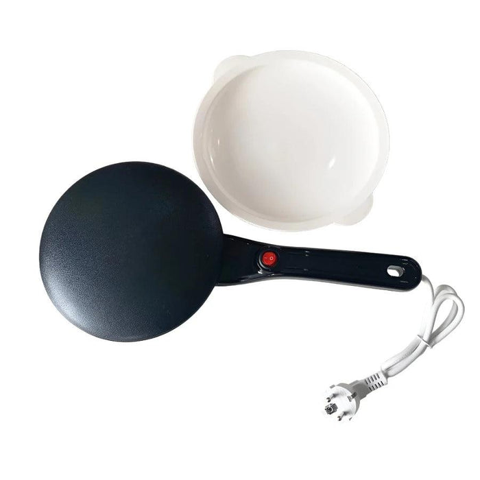 A black electric crepe maker with a black handle, shown with its power cord and a white mixing bowl.