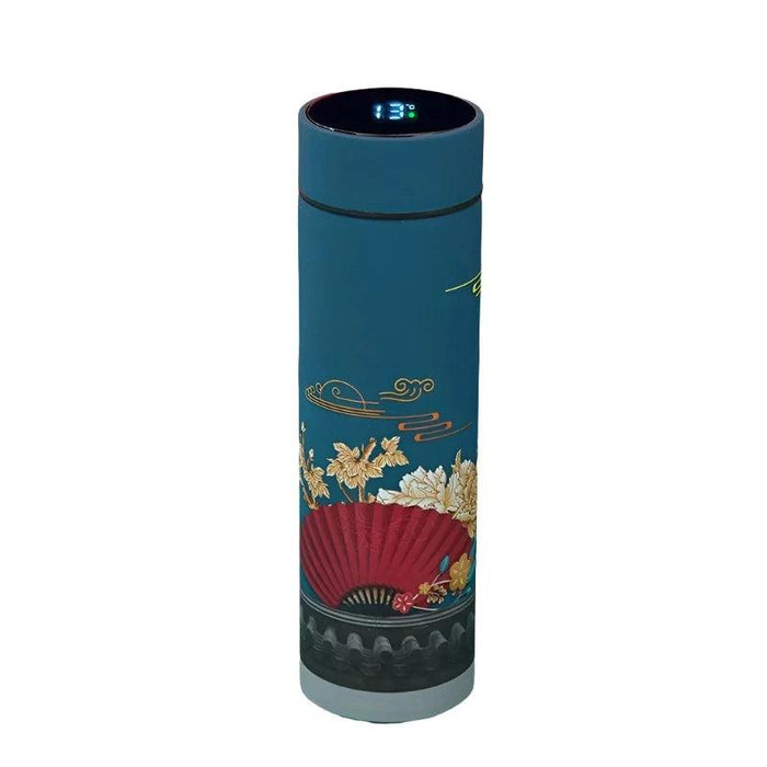 A tall, cylindrical thermos with a green body, adorned with illustrations of flying cranes and ocean waves. The lid, placed next to the thermos, displays a digital temperature reading of 19°C.