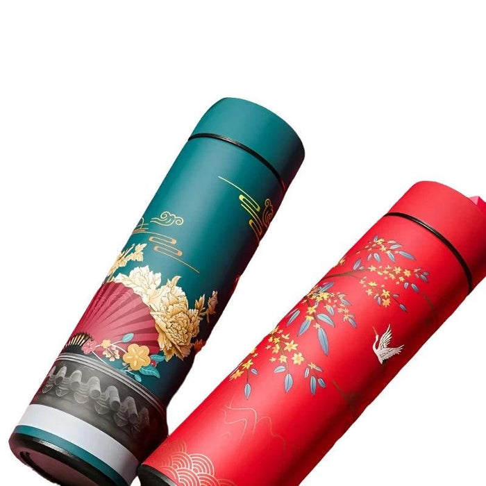 Close-up of two thermoses: one teal with floral and fan design, and one red with blossoms and cranes.