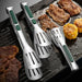 Set of three stainless steel tongs with green accents placed on a grill pan with various grilled foods.