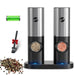 Two black and silver electric grinders with a rechargeable battery and a small brush, filled with salt and peppercorns.