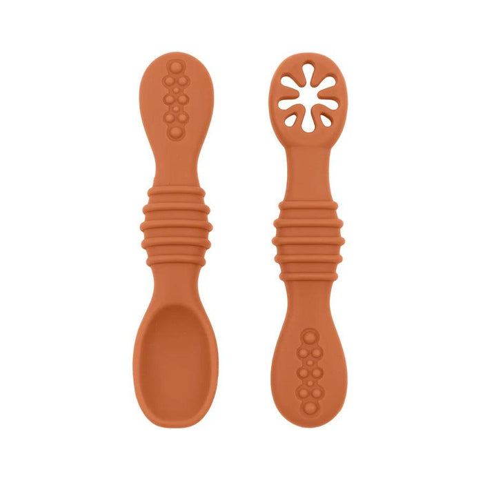 A close-up of two brown baby spoons, one with a regular spoon shape and the other with a cut-out flower design, against a white background.