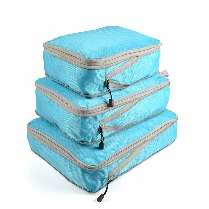 Three sky blue packing cubes with gray zippers and handles, stacked on top of each other. Each cube has a zipper pull with a black tab.