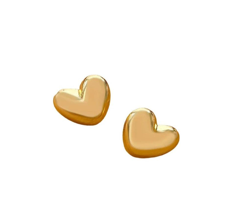 a pair of small, heart-shaped gold stud earrings with a smooth and reflective surface, placed against a white background. These earrings have a classic and elegant design.