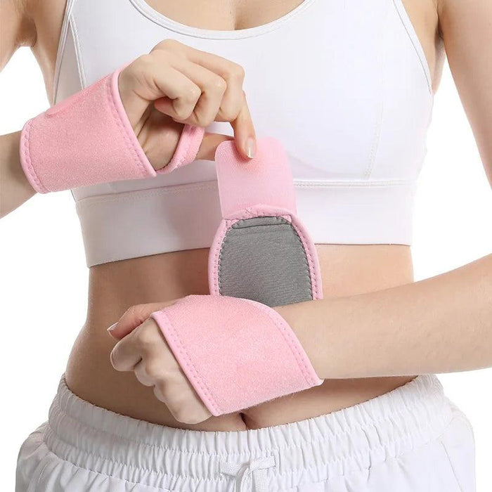 woman is shown from the waist up, wearing the pink wrist support wraps on both wrists. She is adjusting one of the wraps, showing the velcro closure that helps secure it.