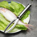 stainless steel fish scaler placed on a plate of fresh lettuce and a whole fish, ready for preparation.