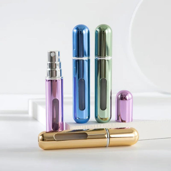 A set of metallic portable perfume spray bottles in purple, blue, green, and gold. One bottle is open, showing the spray nozzle.