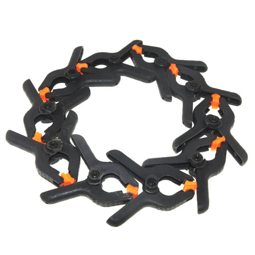 Ten Black Plastic Clamps with orange tip arranged in a circle.