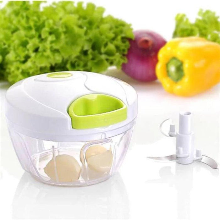 The mini chopper next to some vegetables (onions and bell peppers), with garlic inside the container.