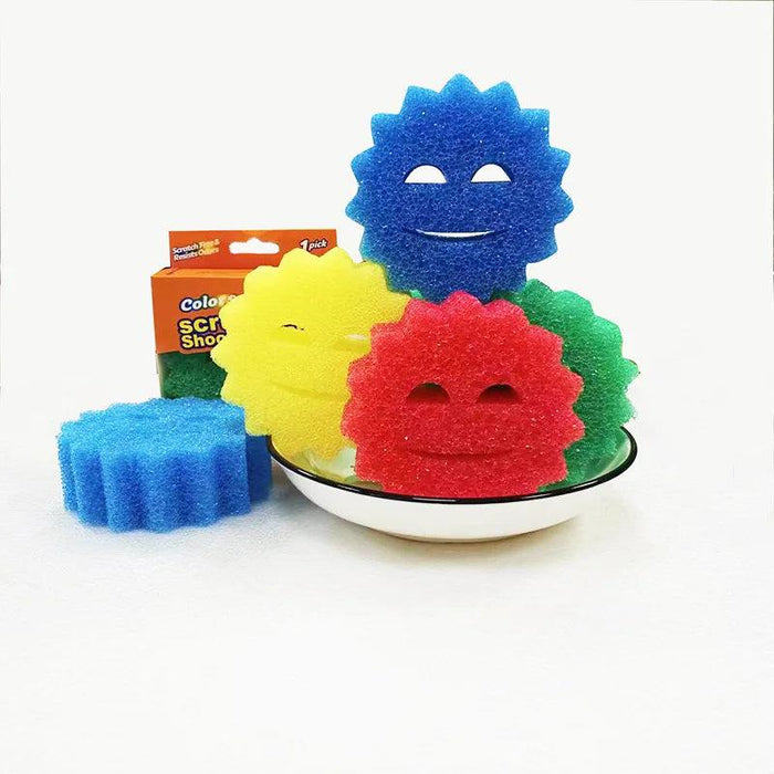 Several sun-shaped scrub sponges in different colors (blue, yellow, green, red) are displayed in a bowl. The sponges are standing upright, showcasing their cheerful, smiling faces.